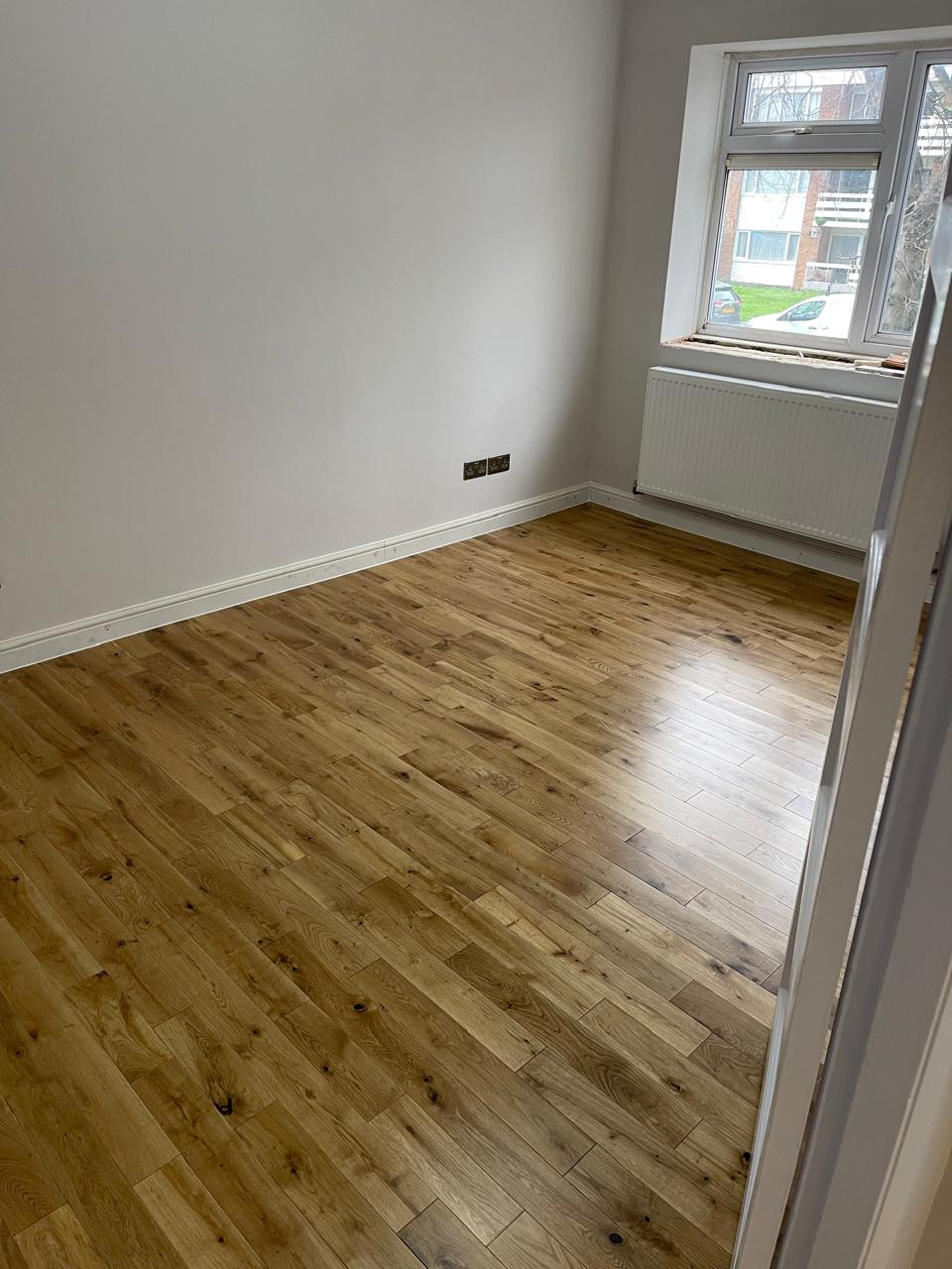 Parket plank lisi në dhomë gjumi me dritare
